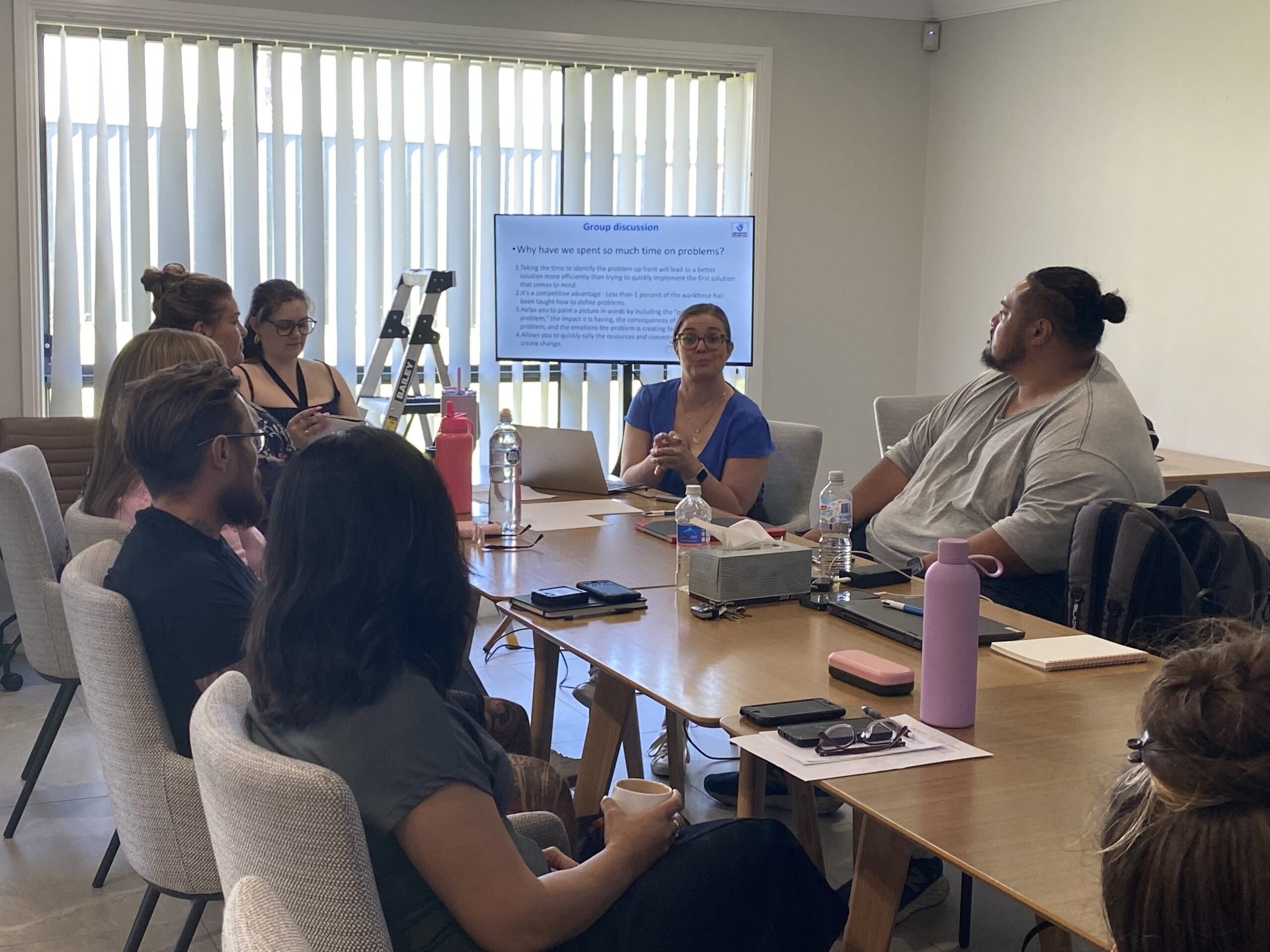 Angela leading a group discussion with a provider team around a boardroom table